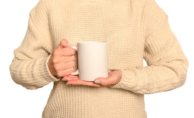 Eine Frau in einem weißen Pullover hält einen weißen Becher Das Konzept von Komfort und Wärme