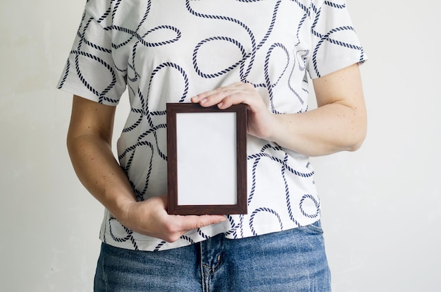 Eine Frau in einem weißen T-Shirt und Jeans hält einen Rahmen in ihren Händen