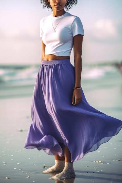 Eine Frau in einem weißen Top und einem lila Rock steht am Strand