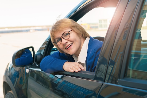 Eine Frau in einer blauen Jacke fährt ein Auto durch die Stadt.