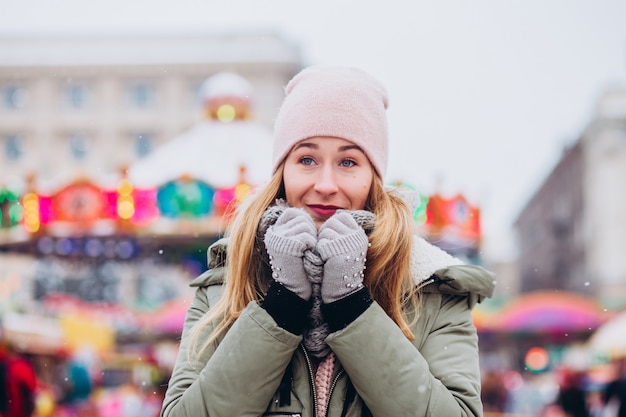 Eine Frau in einer rosa Mütze und einem gestrickten Wollschal geht auf dem Weihnachtsmarkt spazieren