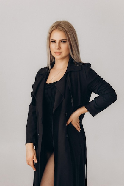 Eine Frau in einer schwarzen Jacke steht vor einem weißen Hintergrund
