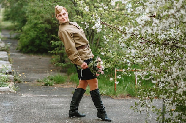 Eine Frau in einer sowjetischen Militäruniform neben einem blühenden Baum