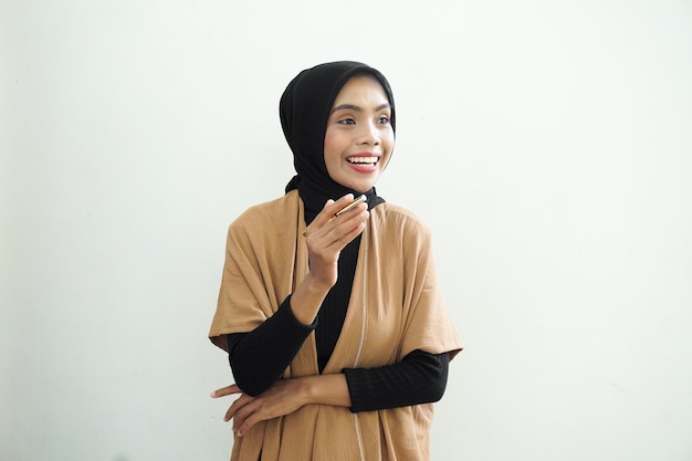 Eine Frau in hellbraunem Kleid und schwarzem Schal steht vor einer weißen Wand.