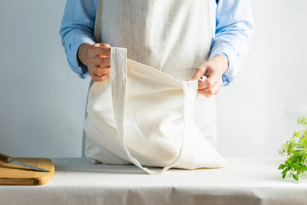 Eine Frau in hellen Kleidern hält eine Baumwolltasche aus natürlichem Stoff Rustikaler natürlicher Stil Kinfolk-Stil Kopierbereich