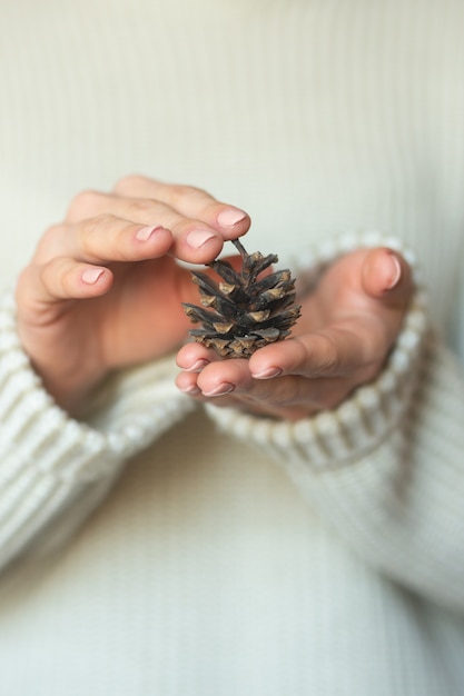 Eine Frau in heller warmer Wolle hält Zapfen in den Händen, kopiert den Raum, wählt den Fokus