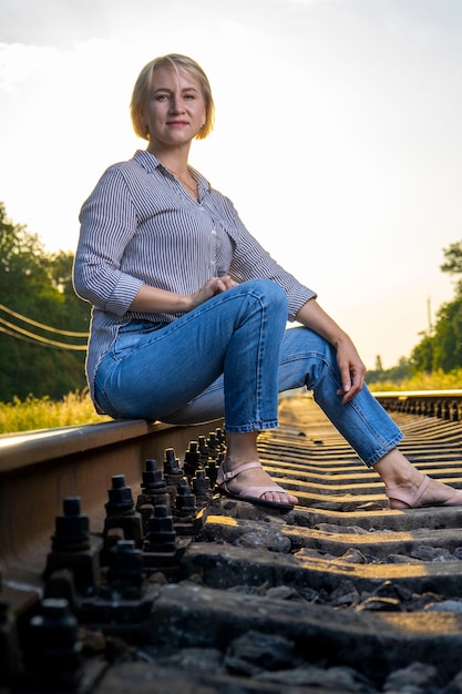 Eine Frau in Jeans sitzt auf einem Bahngleis