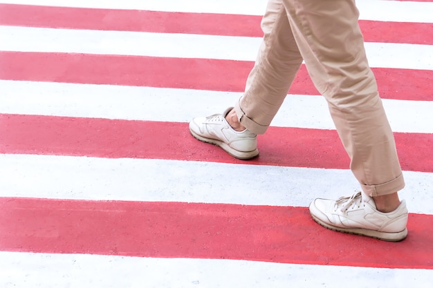 Eine Frau in Sportkleidung überquert einen Fußgängerüberweg in rot-weißen Farben in der Stadt.