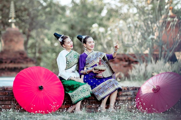 Eine Frau in traditionellen laotischen Kostümen, die während des Songkran-Festivals und des thailändischen und laotischen Neujahrs im Tempel sitzt und Verdienste erbringt