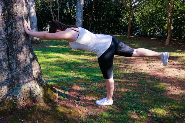 Foto eine frau in voller länge, die am baum steht