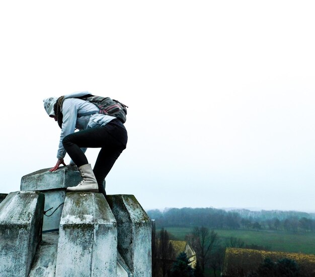 Foto eine frau in voller länge klettert auf eine gebaute struktur gegen einen klaren himmel