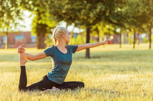Eine Frau in voller Länge übt auf einem grasbewachsenen Feld im Park Yoga
