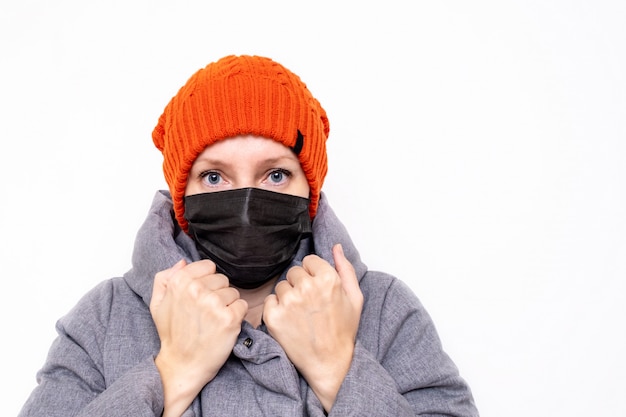 Eine Frau in Winterkleidung trägt eine schwarze Gesichtsmaske als Schutz gegen eine Epidemie von Viruserkrankungen