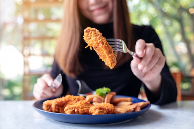 Eine Frau isst gebratenes Huhn und Pommes in einem Restaurant