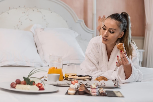 Foto eine frau isst zu hause auf dem bett.