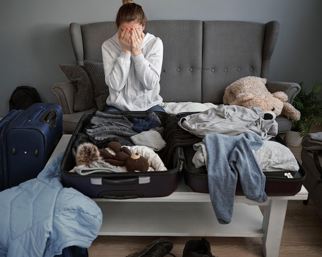 Foto eine frau ist bereit, ihr haus zu verlassen und dinge in einen koffer zu packen frau hand bedeckt gesicht flüchtlinge