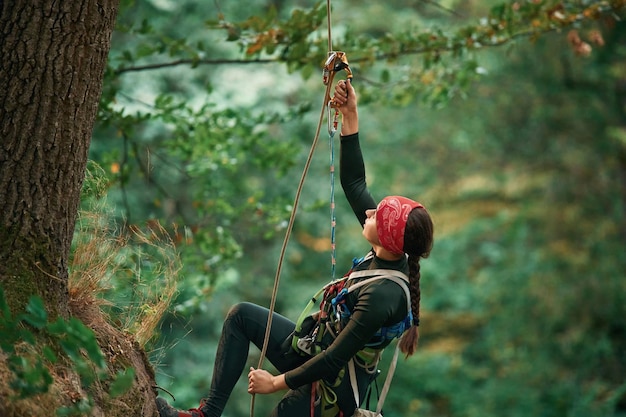 Foto eine frau klettert im wald mit sicherheitsgeräten