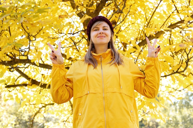 Eine frau lächelt vor einem herbstgelben baum. herbststimmung