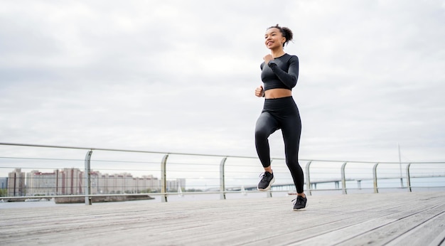 Eine Frau läuft lächelt trainiert Fitness in einem eng anliegenden Trainingsanzug