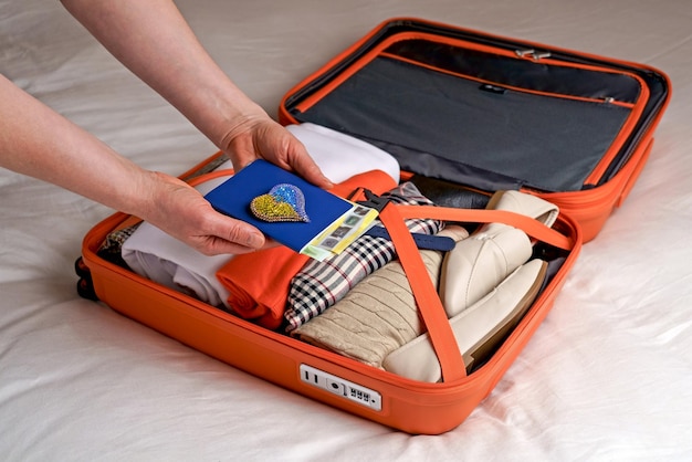 Eine Frau legt Kleidung in einen Koffer auf das Bett, um sich auf einen Wochenendausflug vorzubereiten. Packen Sie Ihr Gepäck und prüfen Sie, ob Sie vor Ihrer Reise etwas vergessen haben