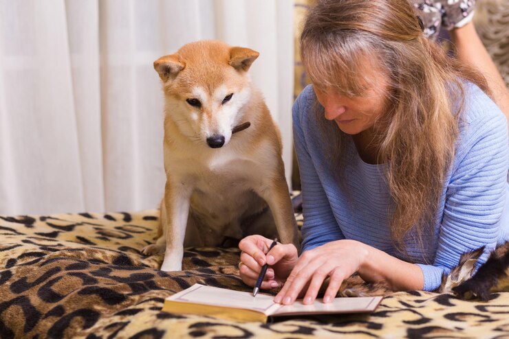 Foto eine frau liegt auf dem bett und schreibt mit ihrem begleiter shiba inu in ein tagebuch. liebe, zweisamkeit und haustiere im haus.