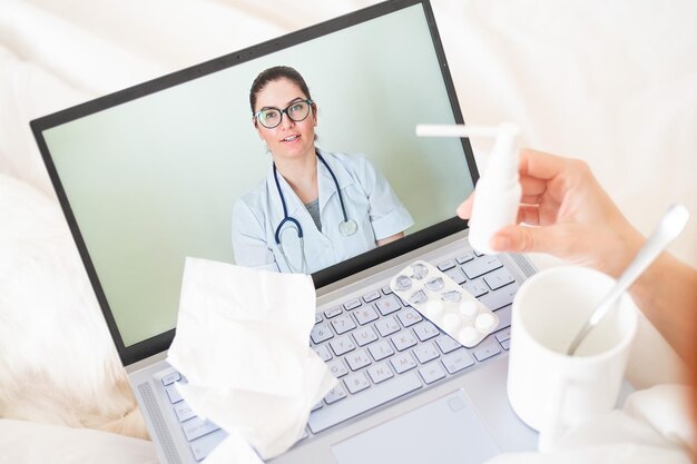 Eine Frau liegt im Bett und hält ein Spray gegen Halsschmerzen Ein freundlicher Arzt spricht per Videoverbindung mit einem kranken Patienten Therapeut auf einem Laptop-Bildschirm Medizinische Online-Beratung während der Quarantäne