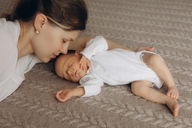 eine Frau liegt mit einem Baby auf einem Bett und das Baby liegt auf dem Boden