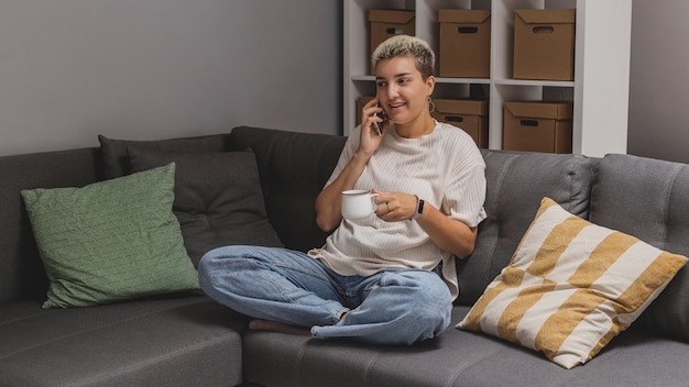 Eine Frau liegt mit einem Smartphone auf einem Sofa in einer minimalistischen Wohnlandschaft