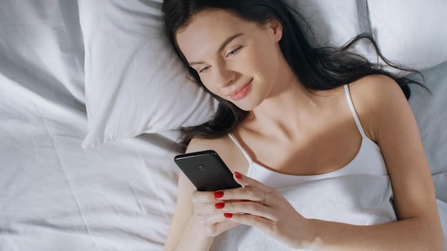 Eine Frau liegt mit einem Telefon in der Hand im Bett