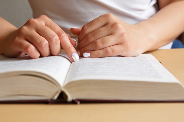 Eine Frau liest ein Buch. Hände halten ein Buch. Schöne Maniküre. Ein Schüler studiert ein Lehrbuch. Das Konzept der Bildung und des Studiums von Informationen