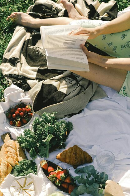 Foto eine frau liest ein buch mit einem bündel gemüse auf dem boden