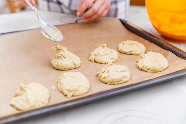 Eine Frau löffelt Cookie-Teig auf ein Backblech Home Backen und Kochen Closeup Selektiver Fokus