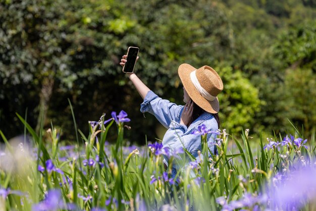 Eine Frau macht ein Selfie mit ihrem Handy auf der Iris-Tectorum-Farm