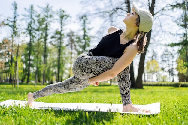 Foto eine frau macht ein yoga-asana-pose-workout im park harmonie und gleichgewicht des körpers verwendet eine matte