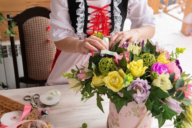 Eine Frau macht einen dekorativen Feiertagsstrauß aus Papierblumen und Süßigkeiten.