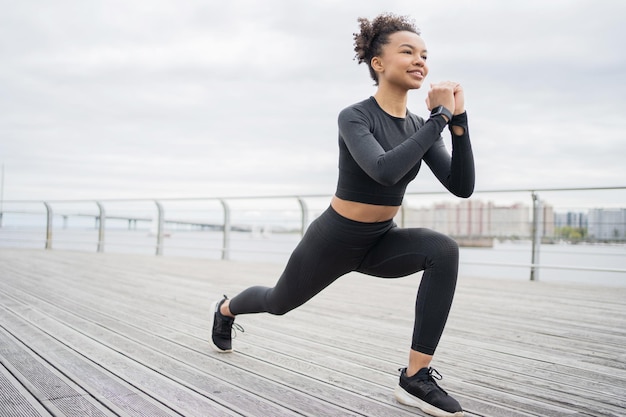 Eine Frau macht Fitnessübungen und verwendet einen Tracker an ihrer Hand, eine intelligente Uhr für das Sporttraining in Sportbekleidung