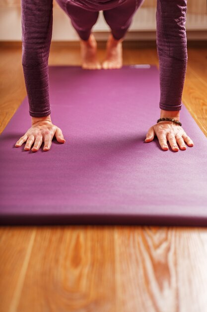 Eine Frau macht Yoga-Asanas auf einem lila Teppich im Wohnzimmer