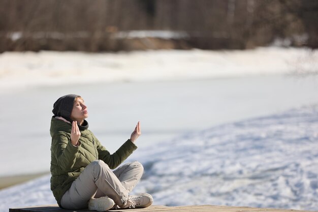 Eine Frau macht Yoga im zeitigen Frühjahr am Fluss