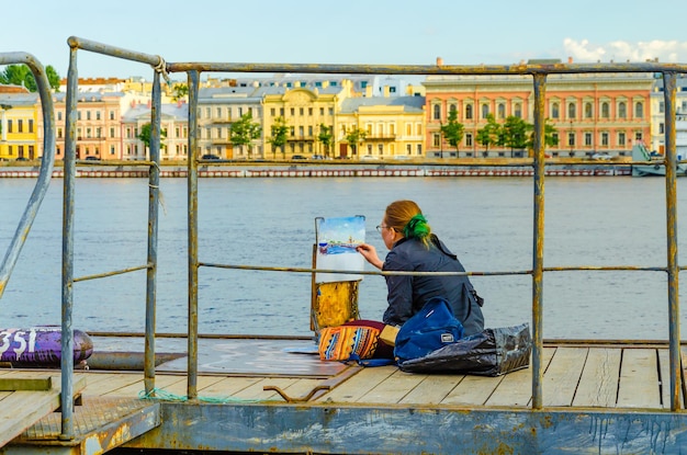 Eine Frau malt ein Bild am Flussufer