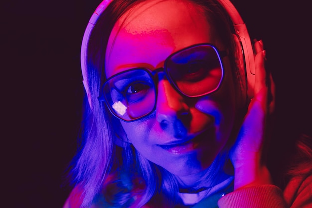 Eine Frau mit Brille und Kopfhörern genießt bei einer Nachtmusik in leuchtenden Farben