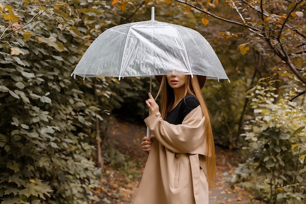 Eine frau mit einem durchsichtigen regenschirm im herbst bei einem spaziergang. nahaufnahme