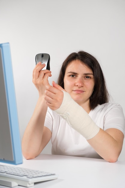 Eine Frau mit einem elastischen Verband am Handgelenk sitzt vor einem Computer