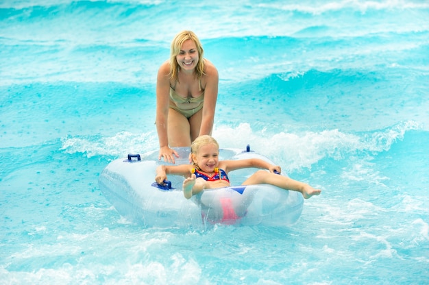 Eine Frau mit einem Kind in einem aufblasbaren Gummikreis spielt im Regen im Pool eines Sommerwasserparks