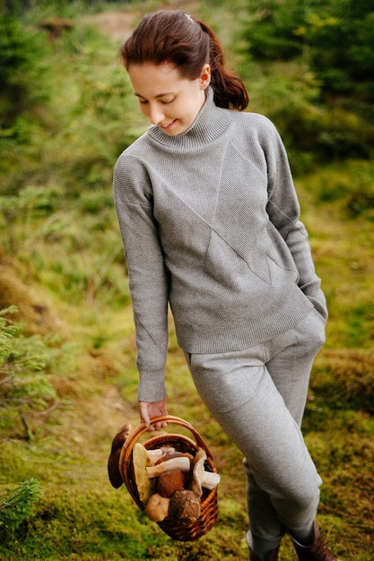 Eine Frau mit einem Korb essbarer Pilze im Wald das Erntesaisonkonzept der Freizeit