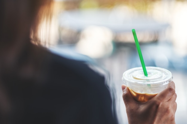 Eine Frau mit einem Plastikglas Eiskaffee mit Strohhalm