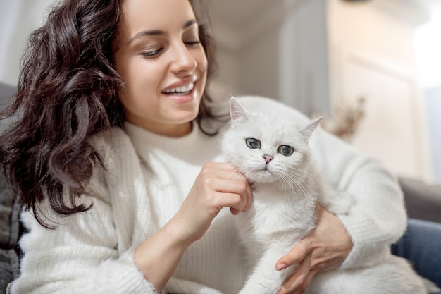 Eine Frau mit einer Katze. Dunkelhaarige junge Frau mit einer schönen weißen Katze