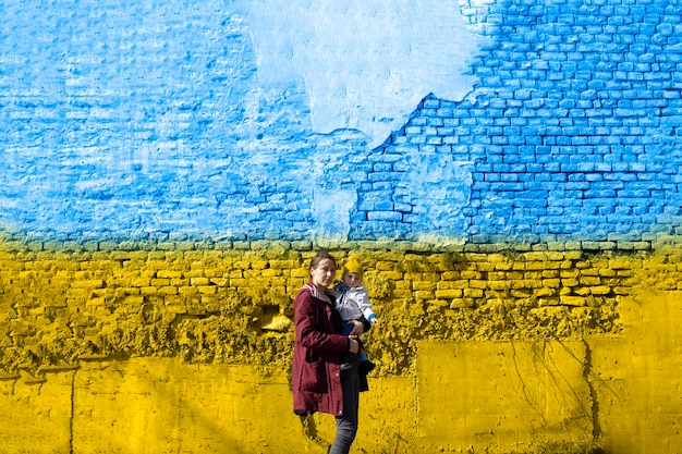 Eine Frau mit ihrem Kind vor ukrainischer Flagge