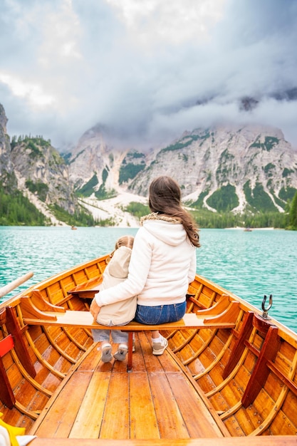 Eine Frau mit ihrer Tochter sitzt in einem großen braunen Boot am Lago di Braies Lake an einem bewölkten Tag in Italien