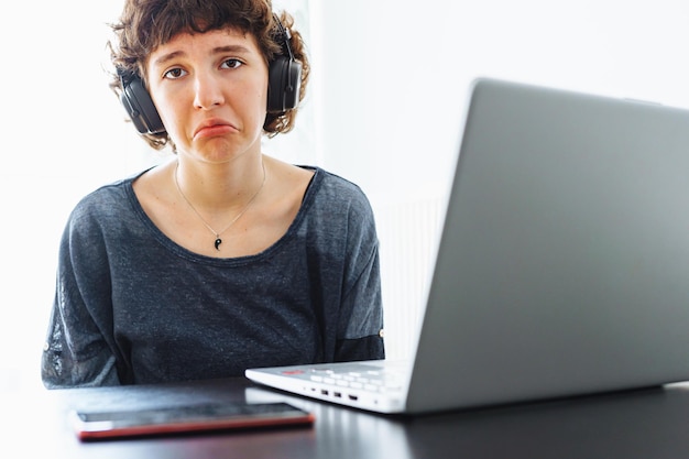 Eine Frau mit Kopfhörern sitzt mit einem Laptop an einem Schreibtisch.