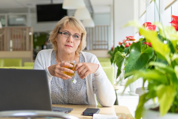 Eine Frau mit Laptop arbeitet in einem Café